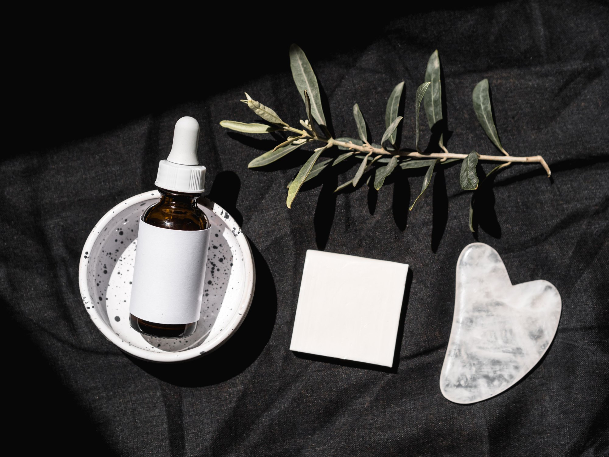 Concept visual: unlabelled skincare products styled on dark linen